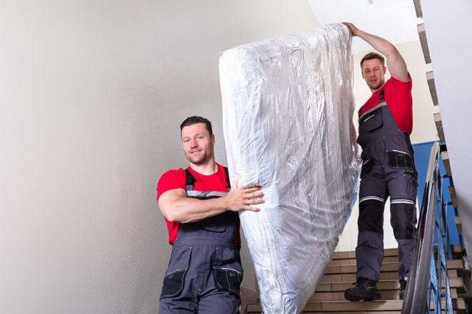 heavy lifting workers transporting a box spring out of a building in Bell Gardens CA